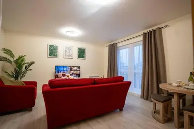 a living room with a red couch and a table at Cosy 2 Bedroom flat in Stevenage in Stevenage