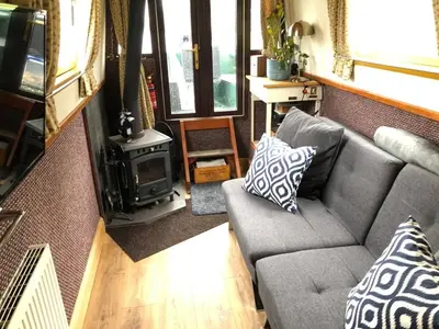 a living room with a couch and a wood stove at Cambridge Narrowboats - Beautiful Narrowboat Glyndwr in Cambridge