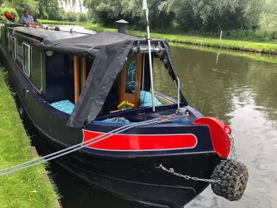 a small boat with a cover on the water at Cambridge Narrowboats - Beautiful New Moon Narrowboat in Cambridge