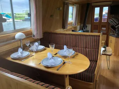 a wooden table with plates and wine glasses on it at Cambridge Narrowboats - Beautiful New Moon Narrowboat in Cambridge