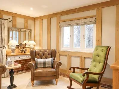 a living room with a chair and a mirror at Lodge Cottage in Harwich