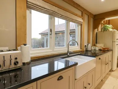 a kitchen with a sink and a large window at Lodge Cottage in Harwich