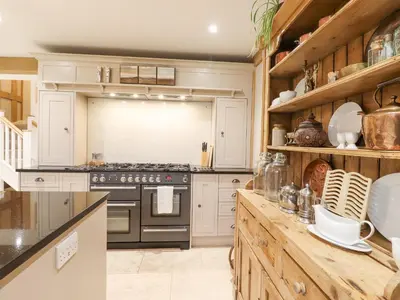 a kitchen with white cabinets and a stove at Lodge Cottage in Harwich