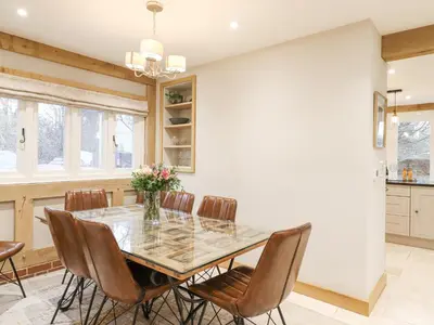 a dining room with a glass table and chairs at Lodge Cottage in Harwich