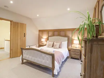 a bedroom with a large white bed and a plant at Lodge Cottage in Harwich