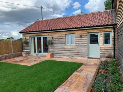 a small house with a yard with green grass at Lodge Cottage in Harwich