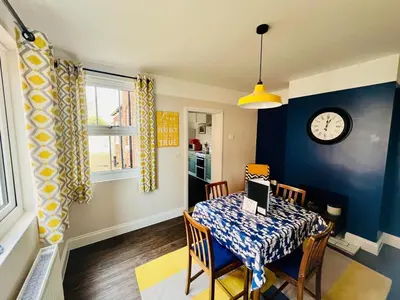 a dining room with a table and a clock on the wall at Countryside Cottage By Walks & Coast, With Parking in Manningtree