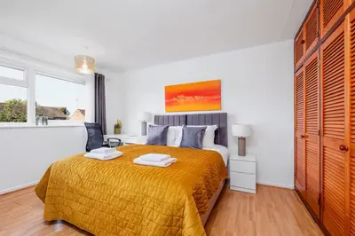 a bedroom with a large bed with a yellow blanket at 4 Bedroom House with Parking & Garden by Cherry Inn Short Let's & Services Accomodation in Cambridge