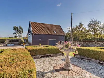 a garden with a building and a vase with flowers at 2 Bed in Diss oc-47778 in Hopton