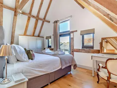 a bedroom with a bed and a desk and windows at 2 Bed in Diss oc-47778 in Hopton