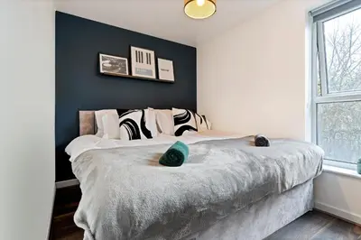 a bedroom with a large bed with a blue wall at Stylish City Centre Apartment with Free Parking, Fast W-fi, Smart TV and Balcony by Yoko Property in Chelmsford