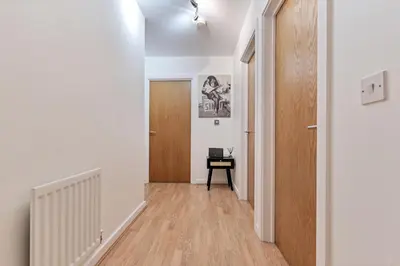 a hallway with white walls and a wooden door at Stylish City Centre Apartment with Free Parking, Fast W-fi, Smart TV and Balcony by Yoko Property in Chelmsford