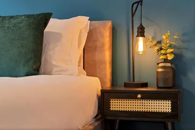 a bed with a lamp on a nightstand next to a bed at Stylish City Centre Apartment with Free Parking, Fast W-fi, Smart TV and Balcony by Yoko Property in Chelmsford