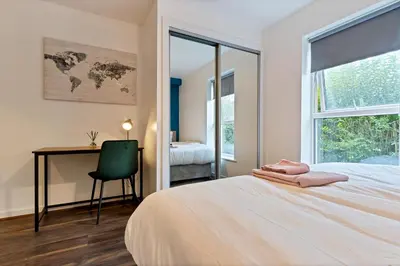 a bedroom with a bed and a desk and a window at Stylish City Centre Apartment with Free Parking, Fast W-fi, Smart TV and Balcony by Yoko Property in Chelmsford