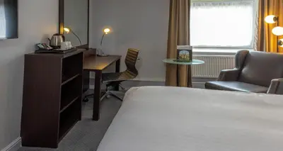 a hotel room with a bed and a desk and a chair at Cambridge Bar Hill Hotel, BW Signature Collection in Cambridge