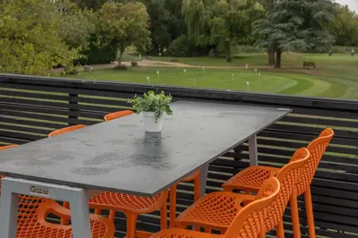 a table with orange chairs and a vase of flowers at Cambridge Bar Hill Hotel, BW Signature Collection in Cambridge