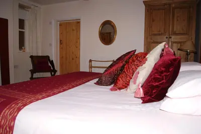 a bed with red and white pillows on it at The Old Pump House in Bungay