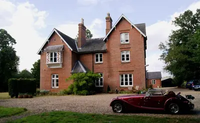 an old red car parked in front of a house at The Old Pump House in Bungay