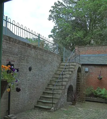 a brick wall with a staircase next to a building at The Old Pump House in Bungay