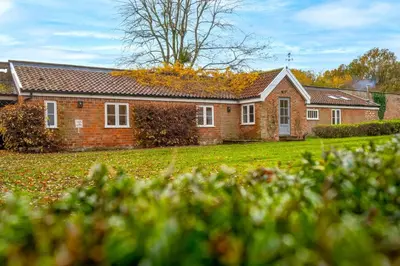 a brick house with a grass yard in front of it at The Pottage in Hoxne