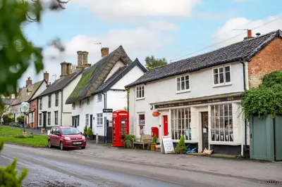 a row of houses with red phone booths on a street at The Pottage in Hoxne