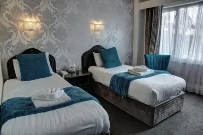 two beds in a hotel room with blue and white towels at The Orwell Hotel in Felixstowe