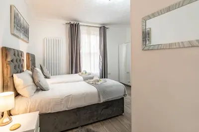 a bedroom with a large bed and a mirror at Prestige Guest House Cambridge Modern Ensuite Rooms in Cambridge