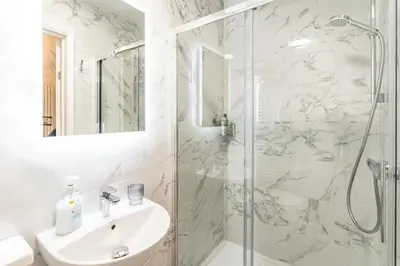 a white bathroom with a shower and a sink at Prestige Guest House Cambridge Modern Ensuite Rooms in Cambridge