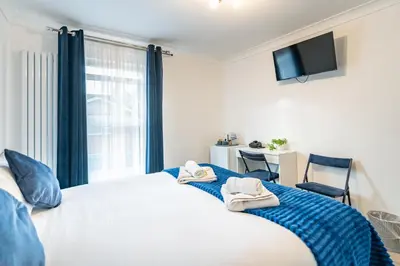 a bedroom with a large bed with towels on it at Prestige Guest House Cambridge Modern Ensuite Rooms in Cambridge