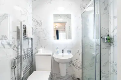 a white bathroom with a sink and a shower at Prestige Guest House Cambridge Modern Ensuite Rooms in Cambridge
