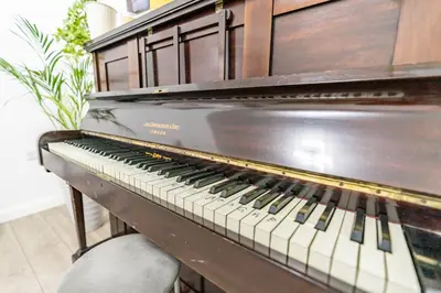 an old piano sitting in a room at Prestige Guest House Cambridge Modern Ensuite Rooms in Cambridge