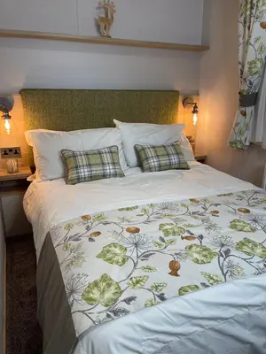 a bedroom with a bed with a green and white comforter at 3 BR - Luxury Family Home Near The Beach in East Mersea