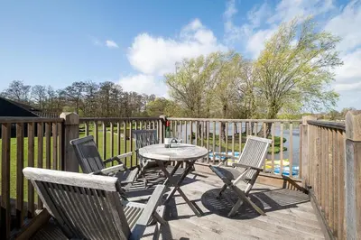 a patio with a table and chairs on a deck at Boat Shelter Cottage in Thorpeness