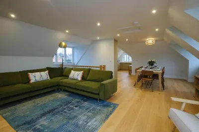 a living room with a green couch and a table at Boat Shelter Cottage in Thorpeness