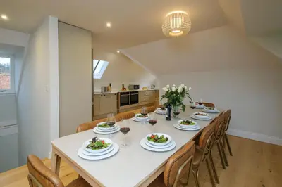 a dining room with a long table with chairs at Boat Shelter Cottage in Thorpeness