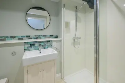 a bathroom with a shower and a sink and a mirror at Boat Shelter Cottage in Thorpeness