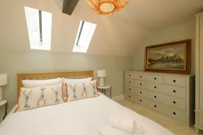 a bedroom with a bed and a painting and a dresser at Boat Shelter Cottage in Thorpeness