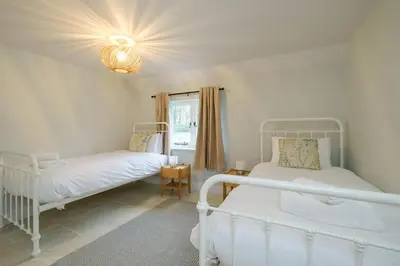 a bedroom with two beds and a window at Boat Shelter Cottage in Thorpeness