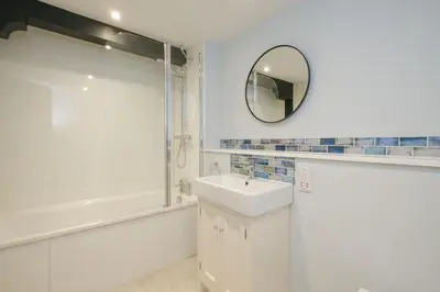a bathroom with a sink and a shower and a mirror at Boat Shelter Cottage in Thorpeness