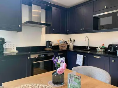 a kitchen with dark blue cabinets and a wooden table at Private Apartment at Woodland Retreat in Gamlingay