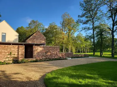a brick house with a gravel driveway at Private Apartment at Woodland Retreat in Gamlingay