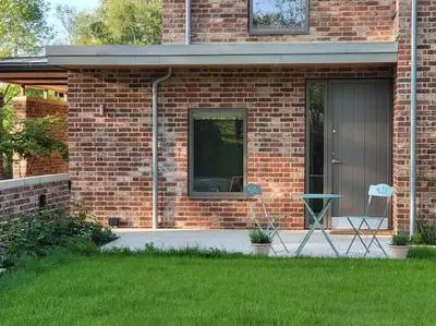 a brick house with a table and chairs in a yard at Private Apartment at Woodland Retreat in Gamlingay