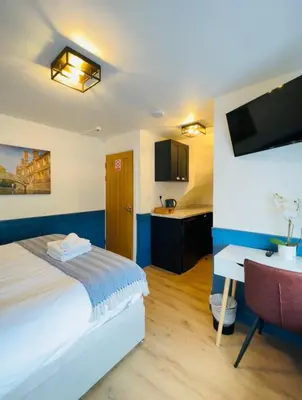 a bedroom with a bed and a desk and a tv at Sun Guest House Cambridge in Cambridge