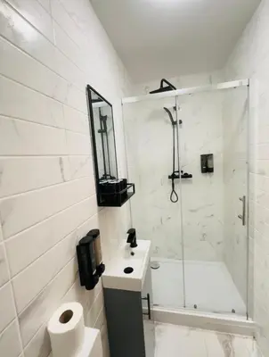 a white bathroom with a shower and a sink at Sun Guest House Cambridge in Cambridge