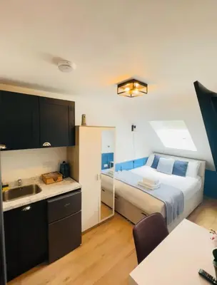 a bedroom with a bed and a kitchen with a sink at Sun Guest House Cambridge in Cambridge