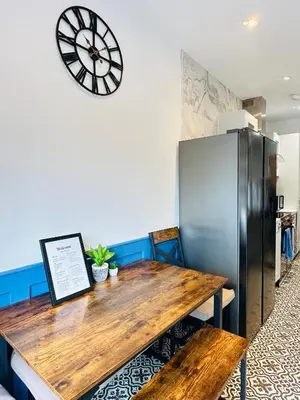 a dining room with a wooden table and a refrigerator at Sun Guest House Cambridge in Cambridge