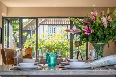 a table with a vase of flowers on it at Luxurious resort house near beach - Mallards in Thorpeness