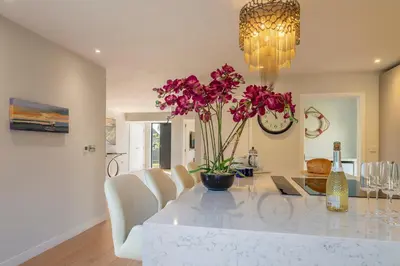 a dining room with a table with purple flowers on it at Luxurious resort house near beach - Mallards in Thorpeness