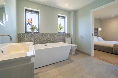 a bathroom with a sink and a toilet and a bed at Luxurious resort house near beach - Mallards in Thorpeness