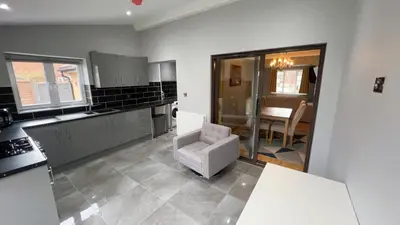 a kitchen with a chair in the middle of a room at Cosy 4 bedroom holiday let Stevenage 22mins from London on the train in Stevenage